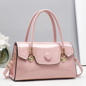 Pink patent leather crossbody handbag with gold shell pendant and top handle design