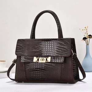 Detail of burgundy crocodile-embossed handbag with gold twist lock and top handle