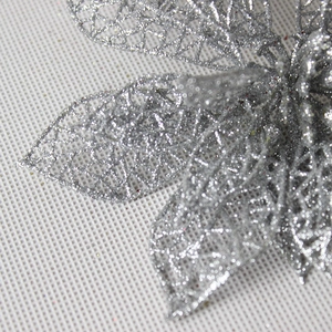 Macro detail of silver glitter poinsettia decoration with hollow mesh petal design