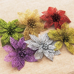 Flat lay of colorful glittery hollowed-out artificial Christmas flowers on linen