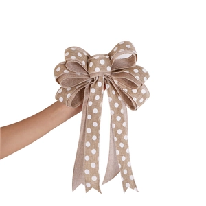 Detail of large natural burlap Christmas bow with white polka dots held by hand