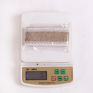 Roll of natural linen burlap ribbon with white lace trim on a digital scale