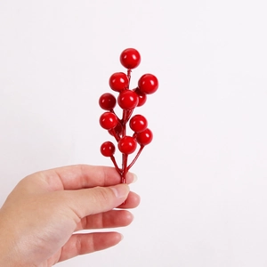 Handheld view of decorative red foam berries on branch for Christmas tree DIY crafts