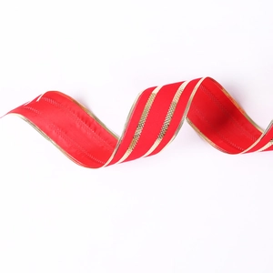 Close-up of red velvet Christmas ribbon featuring golden stripes and woven edges