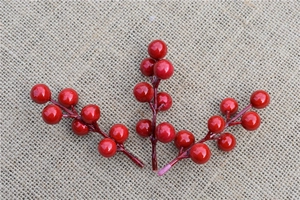 Three artificial red berry branches on a beige burlap texture for Christmas DIY decor