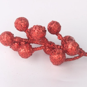 Gros plan de tiges de baies de Noël rouges scintillantes avec paillettes pour sapin