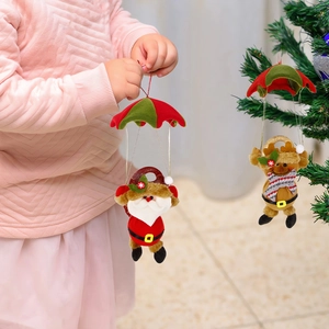 Detail of Santa and reindeer Christmas parachute ornaments hanging on a green tree