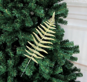 Dettaglio di un ramo di felce dorata glitterata inserito in un albero di Natale verde