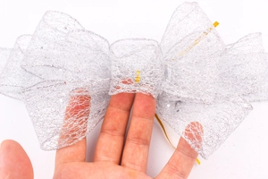 Macro shot of silver glitter mesh bow with gold tie for festive gift decoration