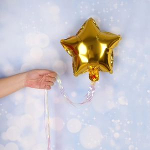 Golden star-shaped foil balloon with iridescent colorful long ribbons for party decor