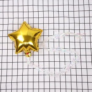 Detail of a gold star foil balloon with iridescent tinsel streamers on a checkered surface