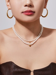 Double-layered pearl necklace with golden spherical beads and matching hoop earrings