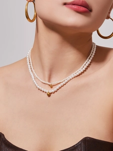 Close-up of elegant double-layered pearl necklace with golden beads on a female model