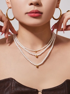 Three-layer pearl necklace with gold ball charms worn by model with gold hoop earrings