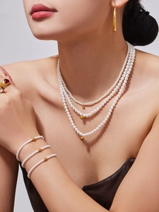 Close-up of triple-layered pearl necklace and bracelet set with golden bead accents
