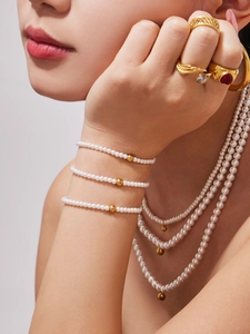 Close-up of pearl bead necklace and bracelet set with gold accents on model