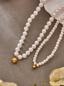 Detailed comparison of large and small pearl necklaces with gold bead pendant accents