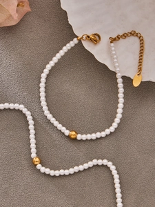 Detailed macro view of white pearl necklace with gold metal beads and lobster clasp closure