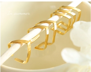 Detailed view of five polished rose gold V-shaped open rings on white supports