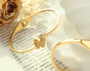 Detail of gold butterfly bracelet with frosted texture and rhinestone on decorative paper