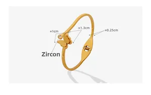 Detail view of gold butterfly open bangle with matte texture and sparkling zircon inlay