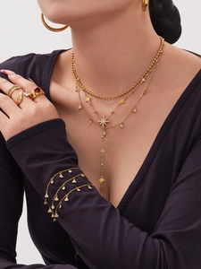 Detailansicht von mehrlagigen Goldketten und Ringen mit Kristallen an einem Modell