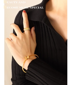 Detail showing a golden butterfly bracelet and pleated metal ring on a female model