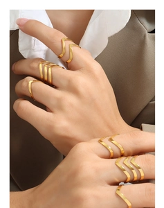 Close-up of polished gold chevron V-shaped rings styled on a model in urban attire