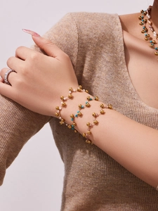Detail of layered gold beaded necklaces and bracelets with blue and white accents
