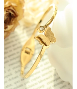 Detailed close-up of golden butterfly open bangle with matte texture and zircon inlay