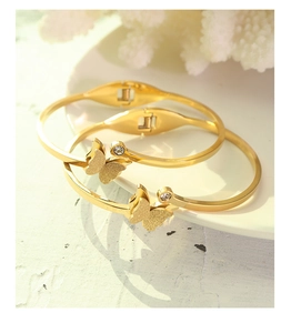 Detail of elegant gold-tone butterfly bangles with matte finish and zircon inlay