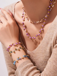 Close-up of layered necklace and bracelet set with natural pearls and purple gemstones