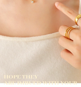 Close-up of 18K gold plated necklace with zircon pendant and stacked sparkling rings