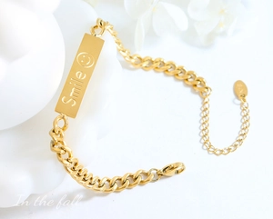 Detailed view of gold plated chain bracelet featuring a smile engraved rectangular plate