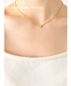 Close-up of a zircon pendant necklace in 18K gold finish worn on a model's neck