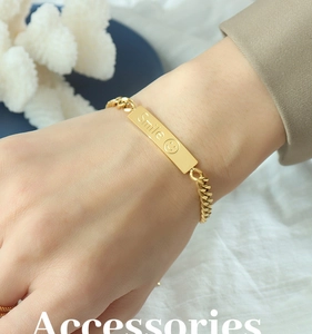Macro shot of 18k gold plated chunky chain bracelet with Smile engraved rectangle charm