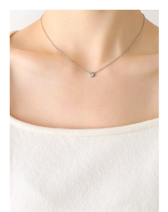 Close-up of a minimalist single zircon pendant necklace worn on a silver-toned chain