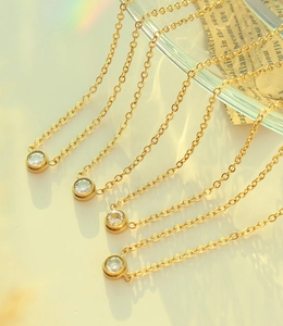 Detailed close-up of 18K gold-plated titanium necklaces with round cubic zirconia pendants