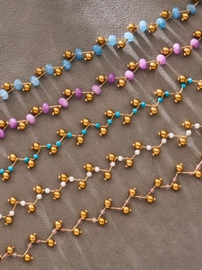 Detail of colorful natural stone bead necklaces with polished golden beads on a grey surface
