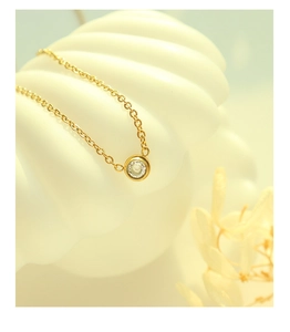 Close-up of elegant gold 18k chain with a single zircon pendant on a white shell