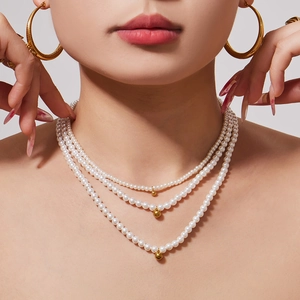 Three-layer pearl necklace with gold bead pendants on an elegant female model