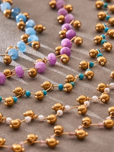 Macro view of gold beaded necklaces with colorful pearl and crystal stone accents