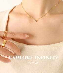 Detail shot of a minimalist 18K gold-plated zircon pendant necklace and stacked rings
