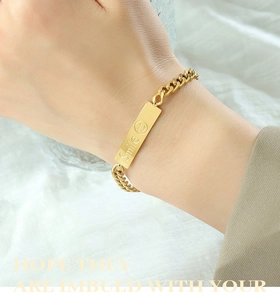 Detail showing gold plated cuban chain bracelet with engraved smile face square charm