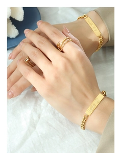 Detailed view of gold stainless steel bracelet featuring an engraved smile plate with ring