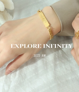 Macro shot of gold-plated bracelet featuring engraved Smile pendant on a linen surface