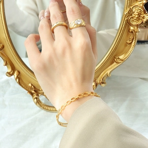 Ensemble bracelet et bagues dorés avec zircons étincelants sur la main d'un modèle