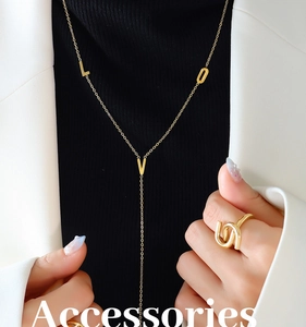Dettaglio della collana dorata LOVE e anello a torsione su modella in blazer bianco