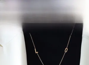 Dettaglio della collana lunga in titanio oro rosa con pendenti a lettere su modella