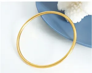 Detail showing matte gold stainless steel bangle on a blue plate with coral decor